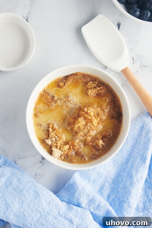 overhead view of graham cracker crumbs, melted butter and brown sugar in a white mixing bowl