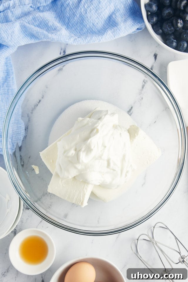 overhead view of cream cheese, sugar, and sour cream in a glass mixing bowl
