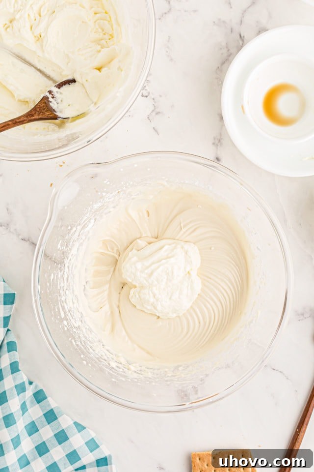 Overhead view of a quarter of the whipped cream being gently folded into the cream cheese mixture for the banana split cake.