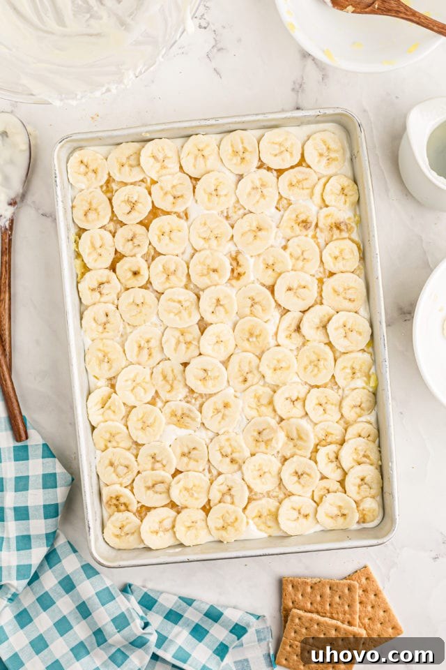 Overhead view of the completed banana layer, covering the pineapple and cream cheese filling.