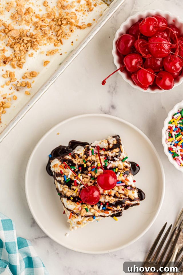 Overhead view of banana split cake on a plate with bowls of cherries and sprinkles, highlighting its vibrant toppings.