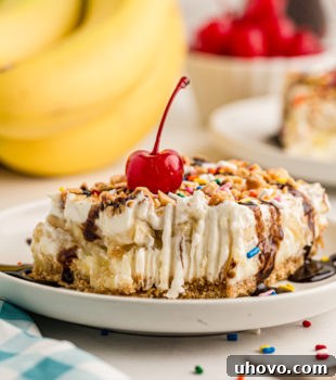 Banana split cake on plate topped with cherry