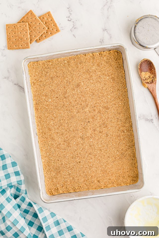 Overhead view of the pressed graham cracker crust evenly spread in a 9x13 inch baking pan.