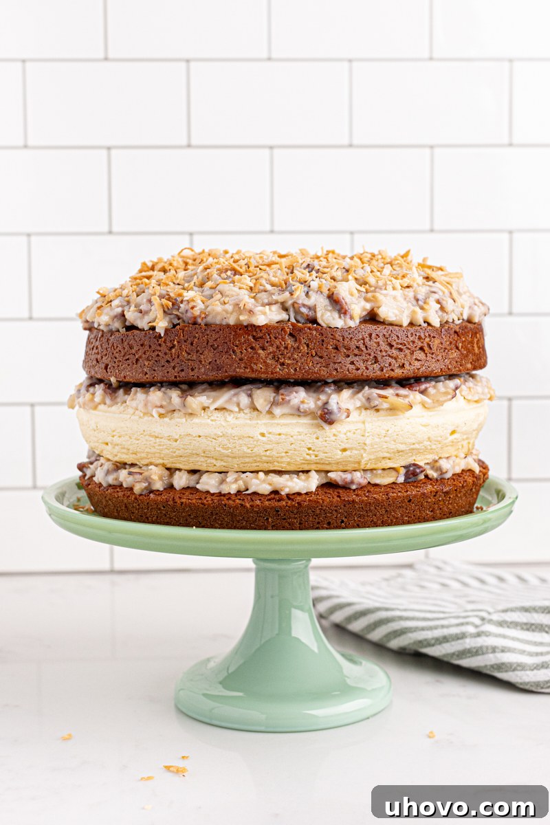 Decadent layered German chocolate cheesecake on an elegant cake stand, showcasing its rich chocolate cake base, creamy cheesecake layer, and abundant coconut-pecan frosting.