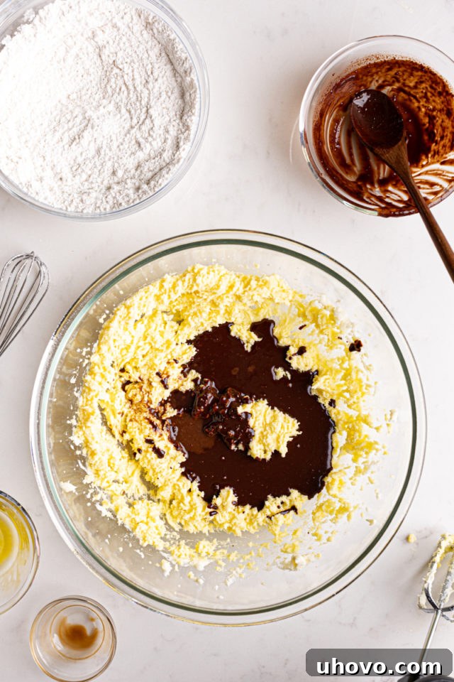 Adding a stream of melted German's sweet chocolate mixture into the creamed butter and sugar, enriching the cake batter.