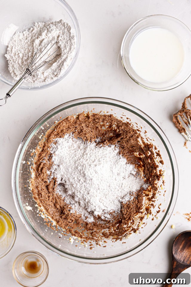 Alternating addition of dry ingredients (flour mixture) and buttermilk into the wet ingredients for German chocolate cake batter.