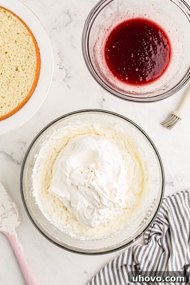 Overhead view of whipped cream added to bowl of cream cheese and mascarpone