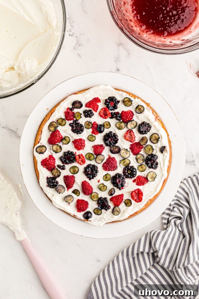 Overhead view of fresh berries added to layer of cake