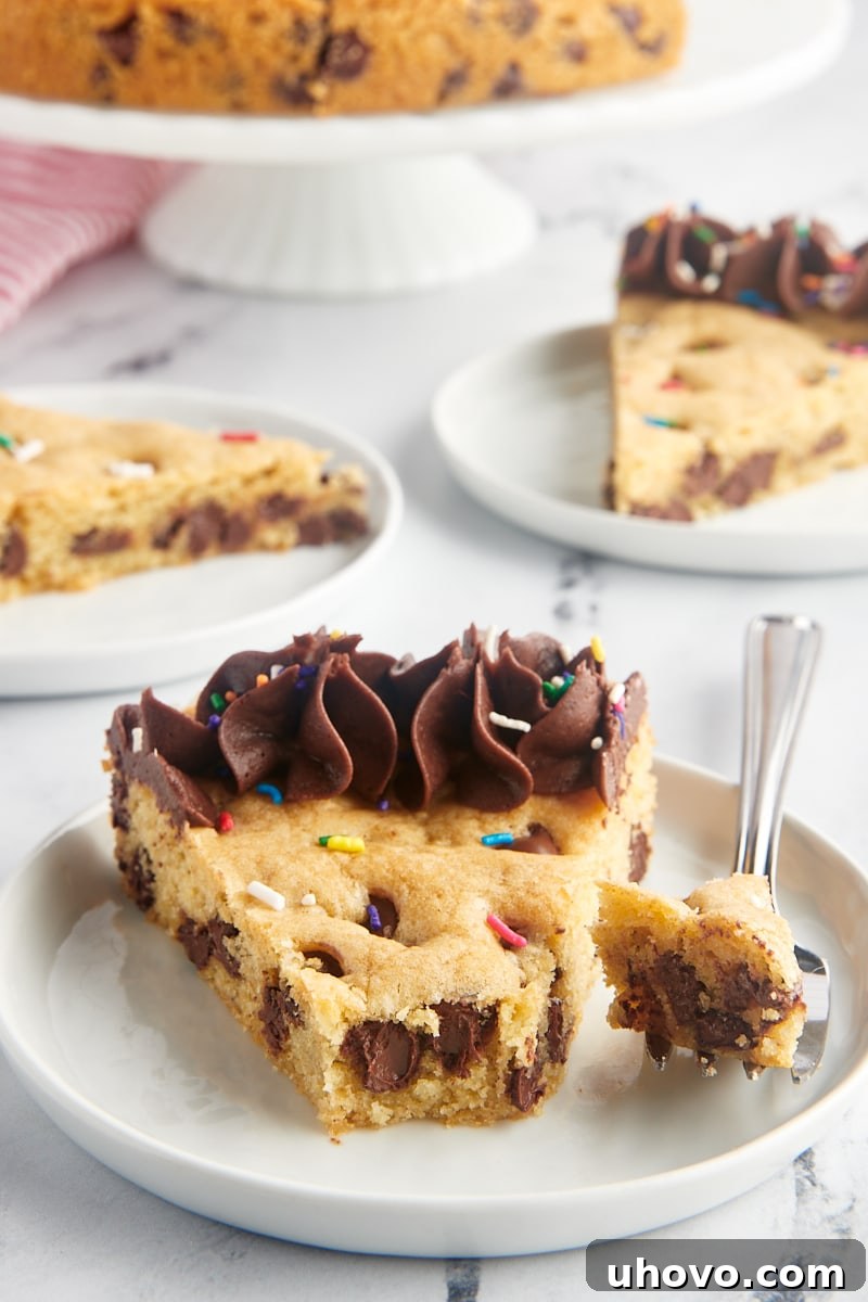 A delectable slice of chocolate chip cookie cake on a white plate, with several more servings artfully arranged in the background, inviting everyone to indulge.