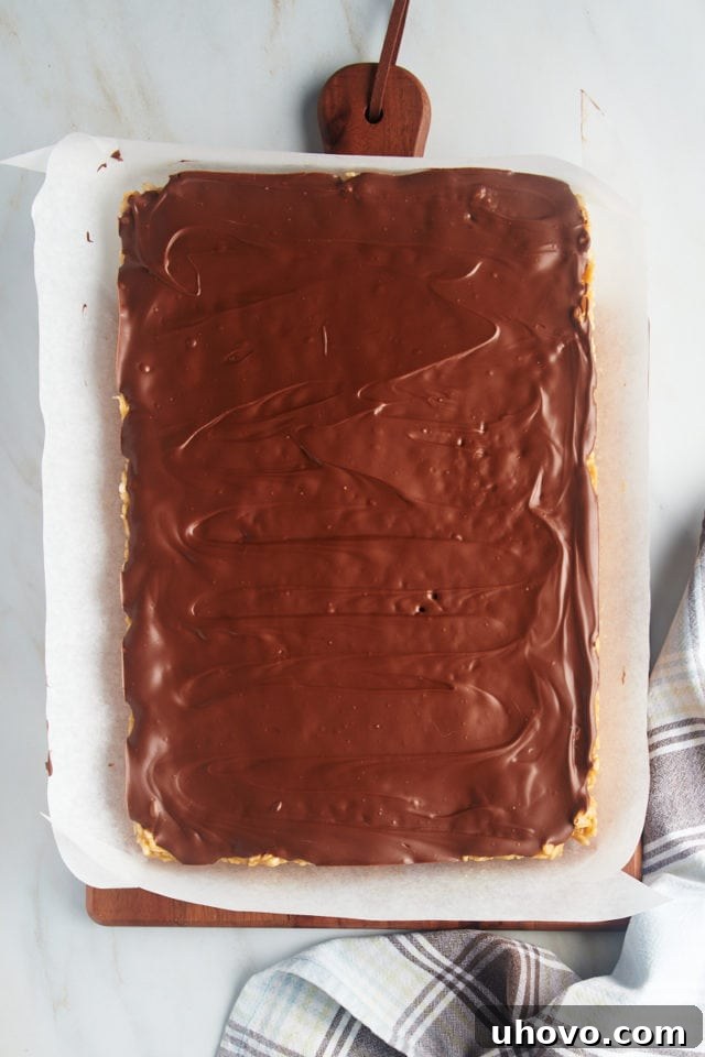 Overhead view of scotcheroos on parchment-lined board before cutting, with topping fully set.