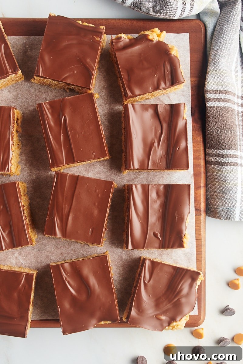 Scotcheroo squares on parchment-lined wooden board, neatly cut and ready to serve.