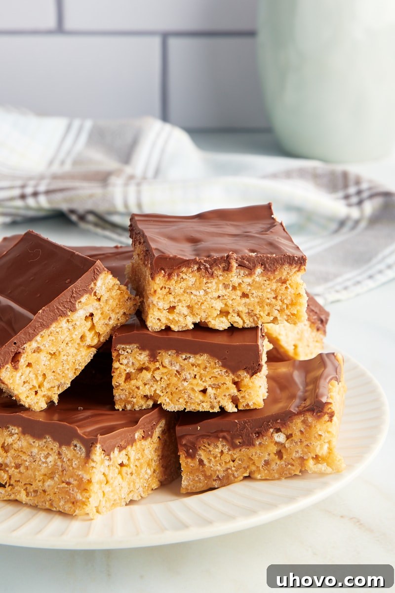 Pile of scotcheroos on white plate, showcasing their inviting texture and rich topping.