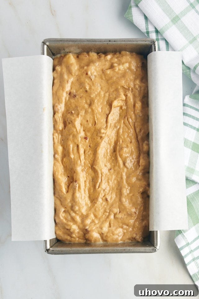 Overhead view of the rich peanut butter banana bread batter carefully spread into the prepared loaf pan, ready for baking.