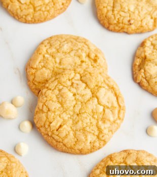 Overhead view of white chocolate macadamia nut cookies with white chocolate chips and macadamia nuts scattered in background