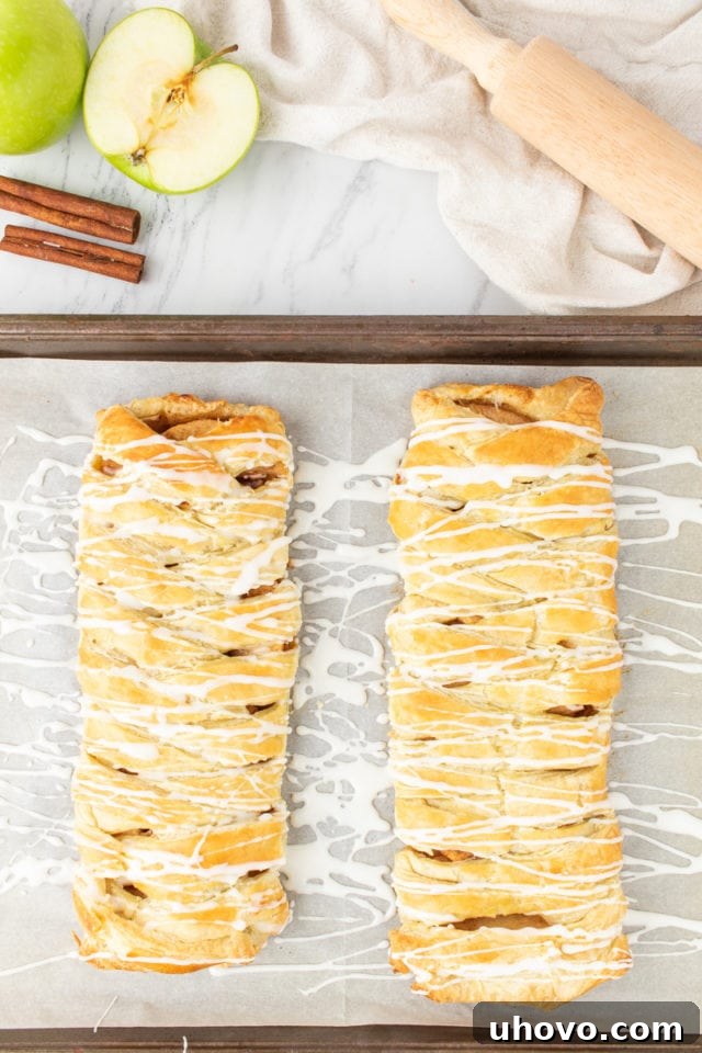 Overhead view of a beautifully glazed apple strudel on a baking sheet, with a delicate drizzle of icing, ready to be served.