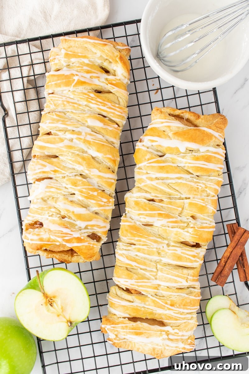 Overhead view of two perfectly baked and glazed apple strudel pastries resting on a wire rack, cooling and ready to be enjoyed.