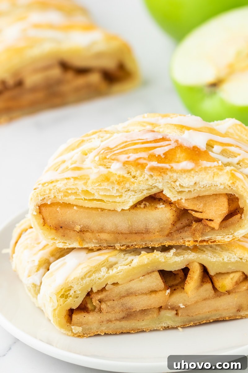 Two enticing slices of golden-brown apple strudel, stacked on a pristine white plate, showcasing the flaky pastry and juicy apple filling.