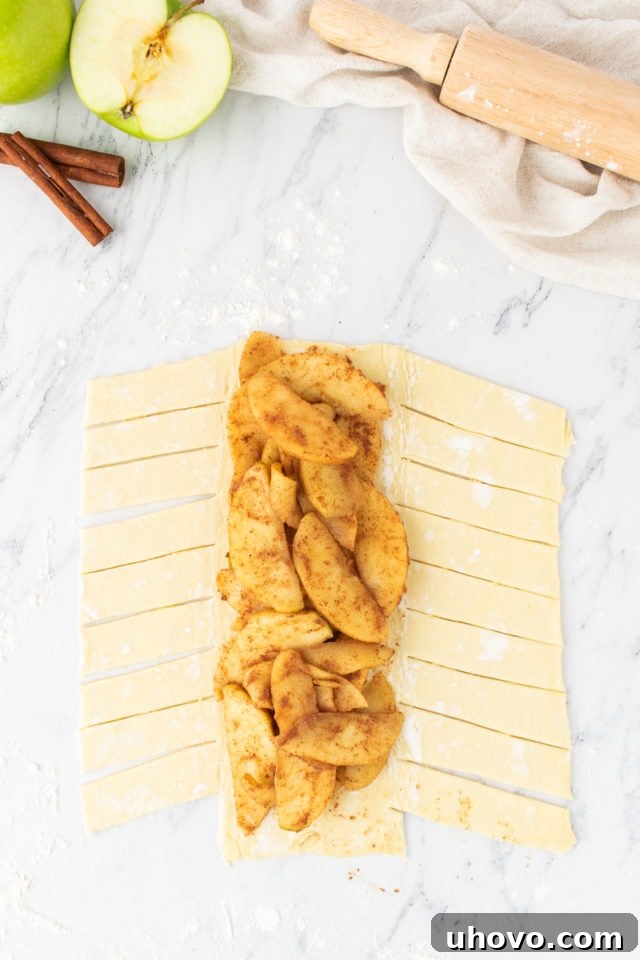Overhead view of the spiced apple filling spread neatly down the center of the prepared puff pastry sheet.