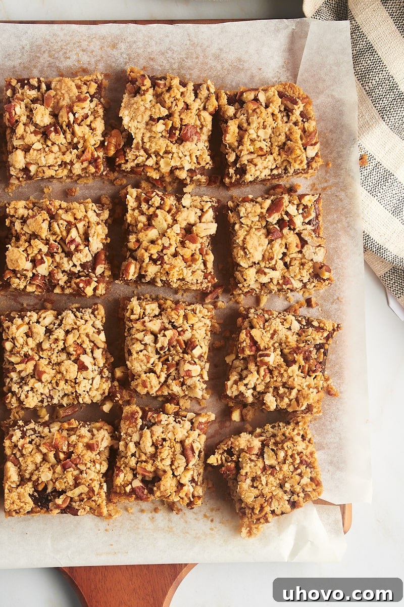 Close-up overhead view of neatly cut date bars arranged on a parchment-lined cutting board, ready for serving.