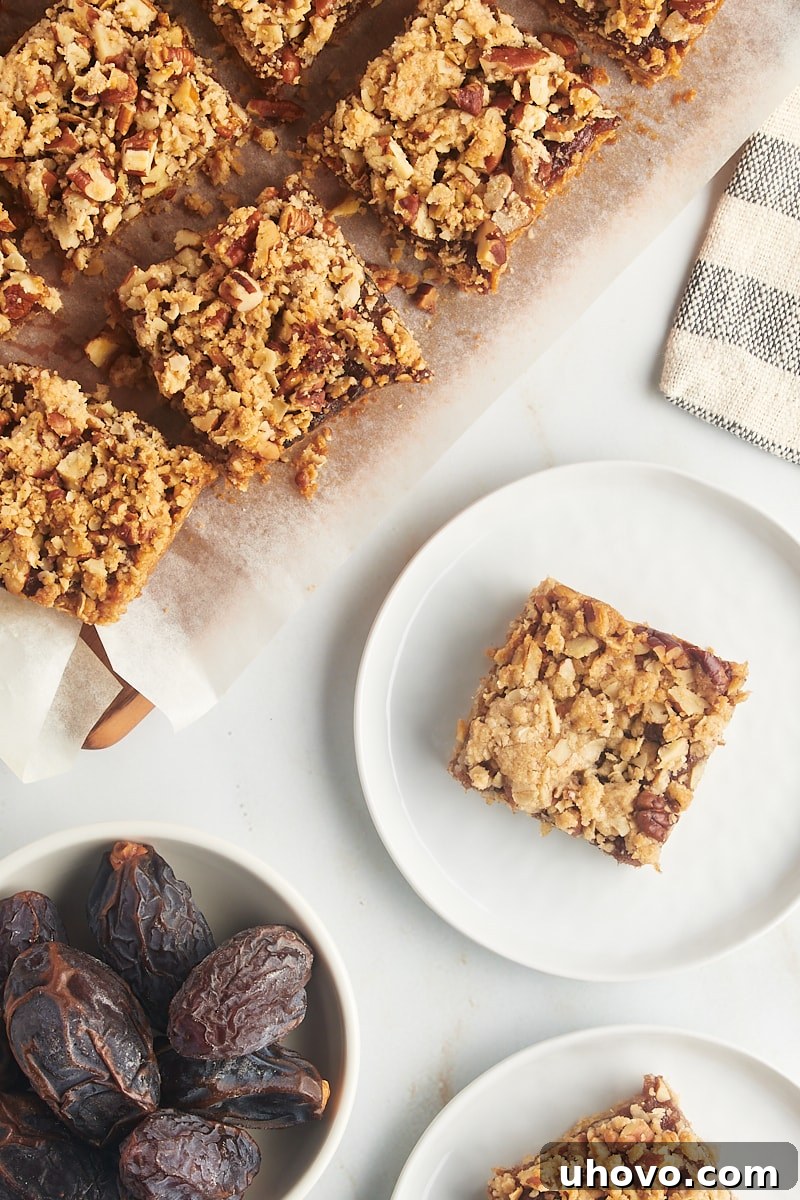 Overhead view of several date bars arranged on individual plates and more on a parchment-lined cutting board, ready to be enjoyed.