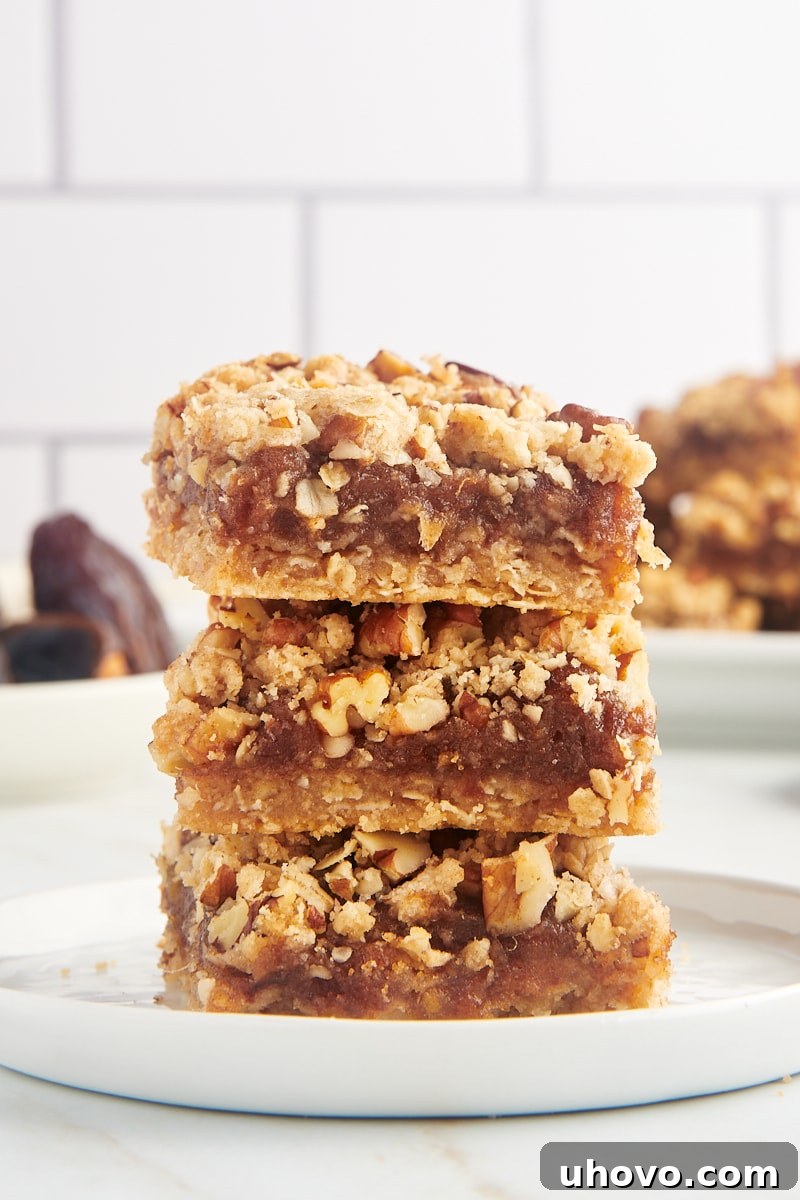 Three perfectly baked date bars stacked neatly on a white plate, highlighting their golden crust and rich filling.