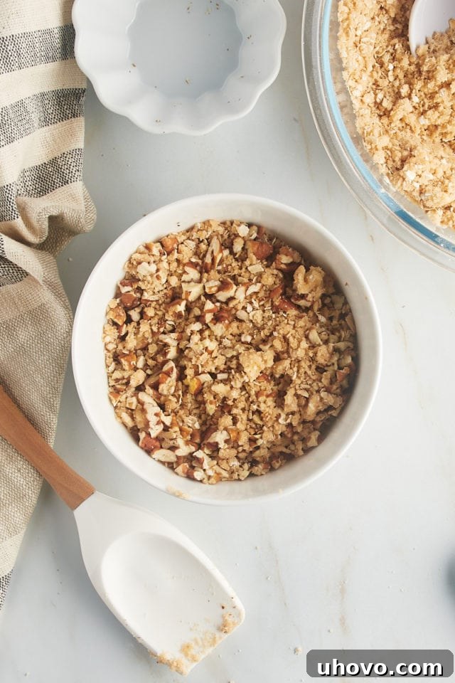 Overhead view of the nutty topping mixture in a mixing bowl, featuring oats, flour, and chopped nuts.