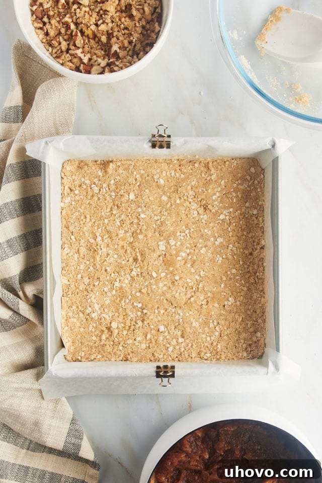 Overhead view of the oat crust pressed evenly into the bottom of a square baking pan.