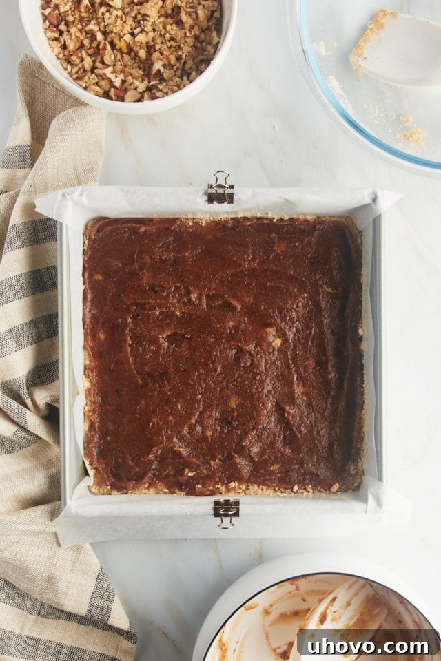 Overhead view of the luscious date filling spread smoothly over the prepared oat crust in the baking pan.