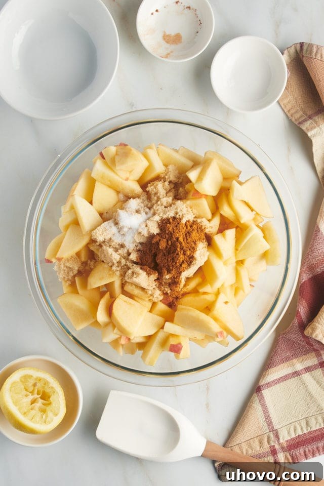 Overhead view of sliced apples in a mixing bowl with cinnamon, brown sugar, and salt.