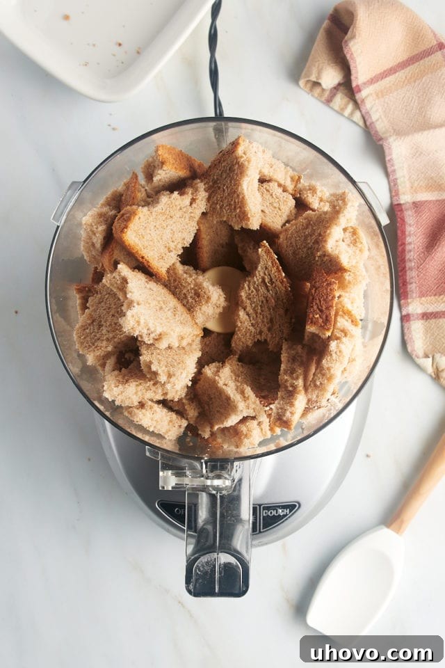 Overhead view of torn bread pieces in food processor bowl, ready for processing.