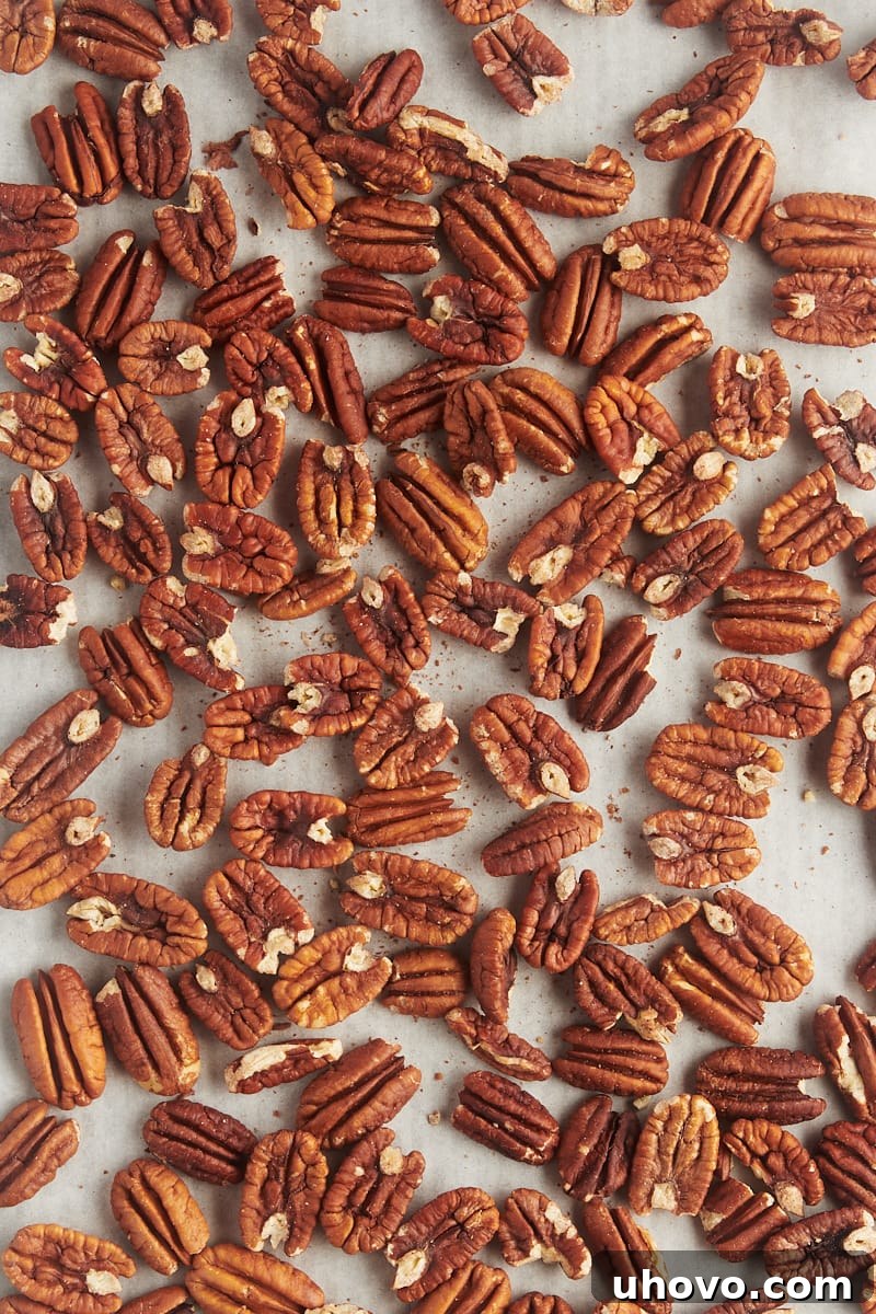 overhead view of toasted pecans on a sheet of parchment paper