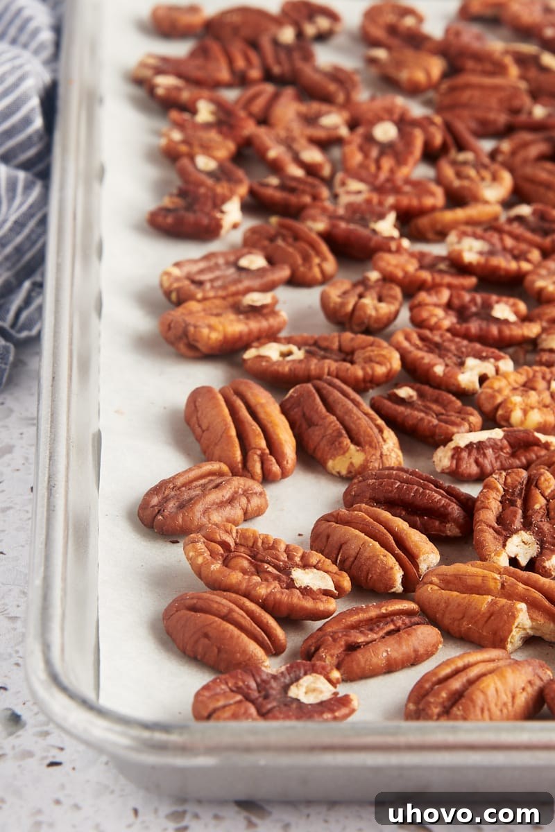 toasted pecans on a baking sheet lined with parchment paper