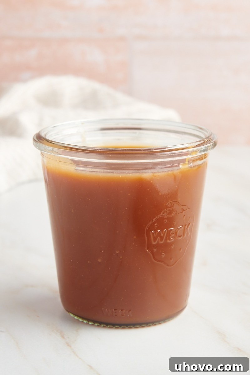A beautifully rich caramel sauce poured into a clear glass jar, ready for storage or immediate use.