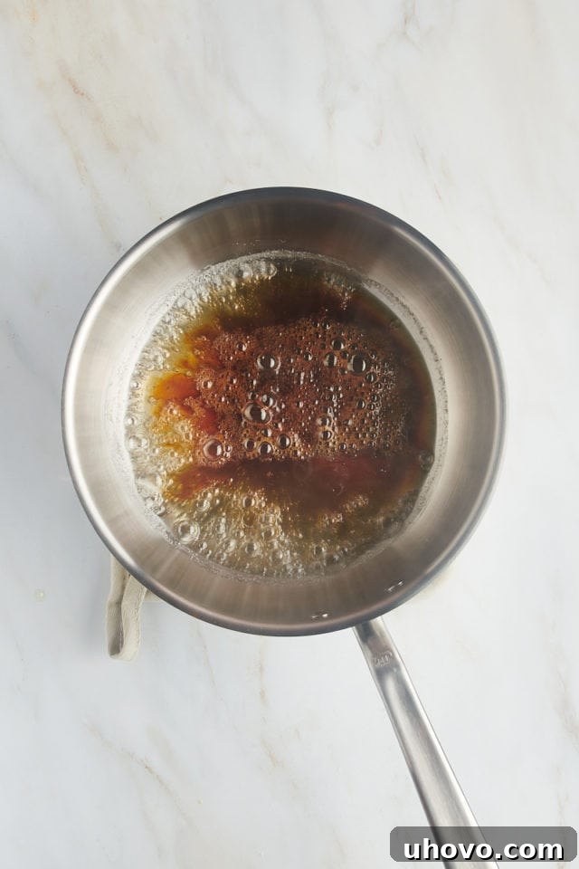 Overhead view of deeply caramelized sugar, a rich amber hue, ready for the next step in a saucepan.