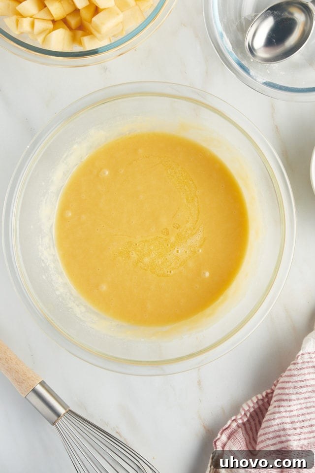 An overhead view of the beautifully mixed batter for French apple cake, showcasing its smooth, thick, and consistent texture in a glass bowl.