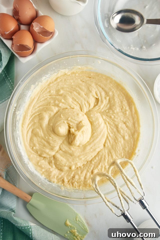 An overhead view of the fully mixed Louisiana Crunch Cake batter, smooth and ready to be transferred, resting in a clear glass mixing bowl.