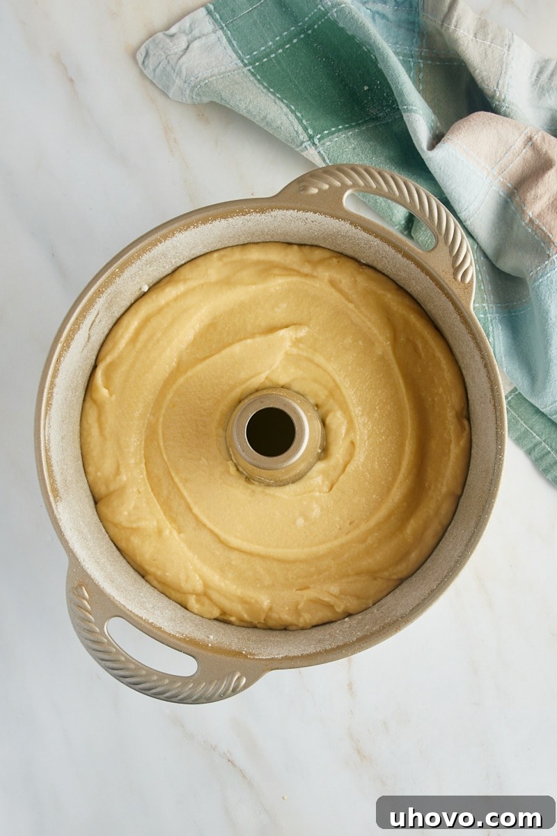 An overhead view of the rich Louisiana Crunch Cake batter carefully spooned into a sugar and coconut-coated tube pan, ready for baking.