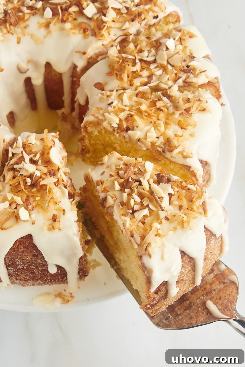 A perfectly baked slice of Louisiana Crunch Cake being gracefully lifted from the rest of the cake on a cake server, highlighting its moist interior and crunchy exterior.