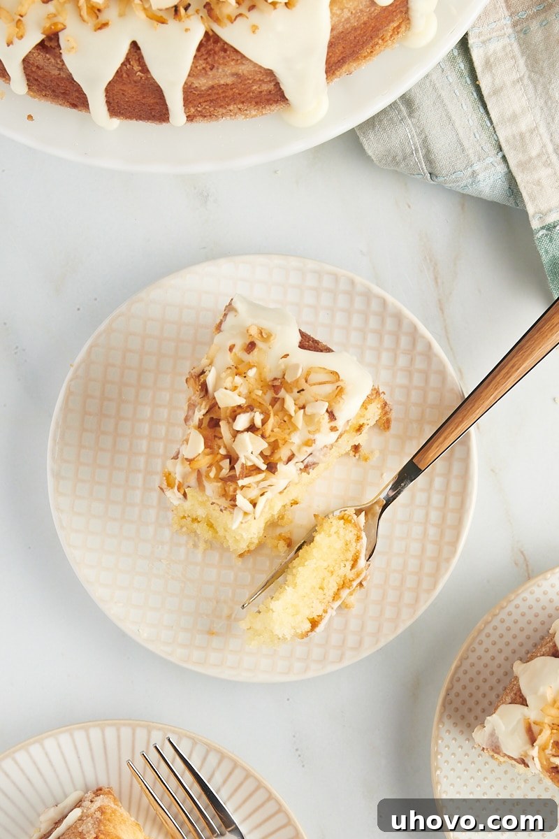 An overhead view of a single slice of Louisiana Crunch Cake, beautifully presented on a white and beige plate, with a fork holding a bite of cake, highlighting its irresistible texture.