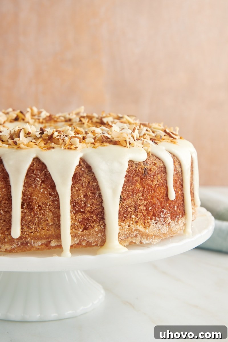 The magnificent Louisiana Crunch Cake displayed prominently on an elegant white cake stand, showcasing its perfect shape, glistening glaze, and inviting toppings.