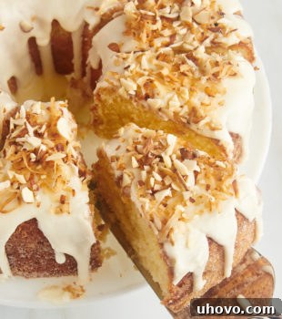 A slice of Louisiana Crunch Cake on a cake server being removed from the remaining cake, highlighting its perfect texture and glaze.