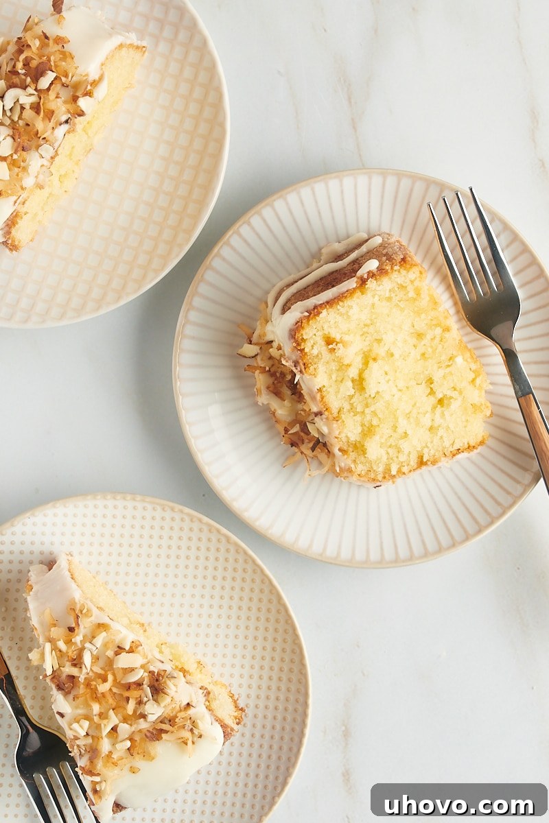 Three perfectly presented slices of Louisiana Crunch Cake, each on its own elegant white and beige plate, highlighting the delicious glaze and crunchy toppings.