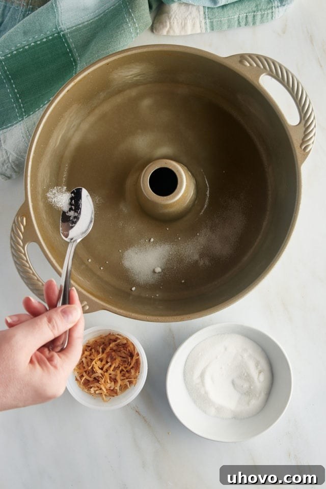 An overhead view of granulated sugar being meticulously sprinkled into the bottom of a tube pan, preparing the base for the signature crunchy crust of the Louisiana Crunch Cake.
