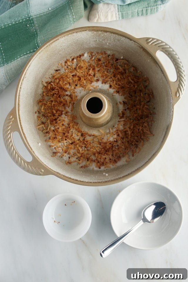 An overhead view of the meticulously prepared Bundt pan, coated with both sugar and toasted coconut, forming the crunchy base for the Louisiana Crunch Cake.