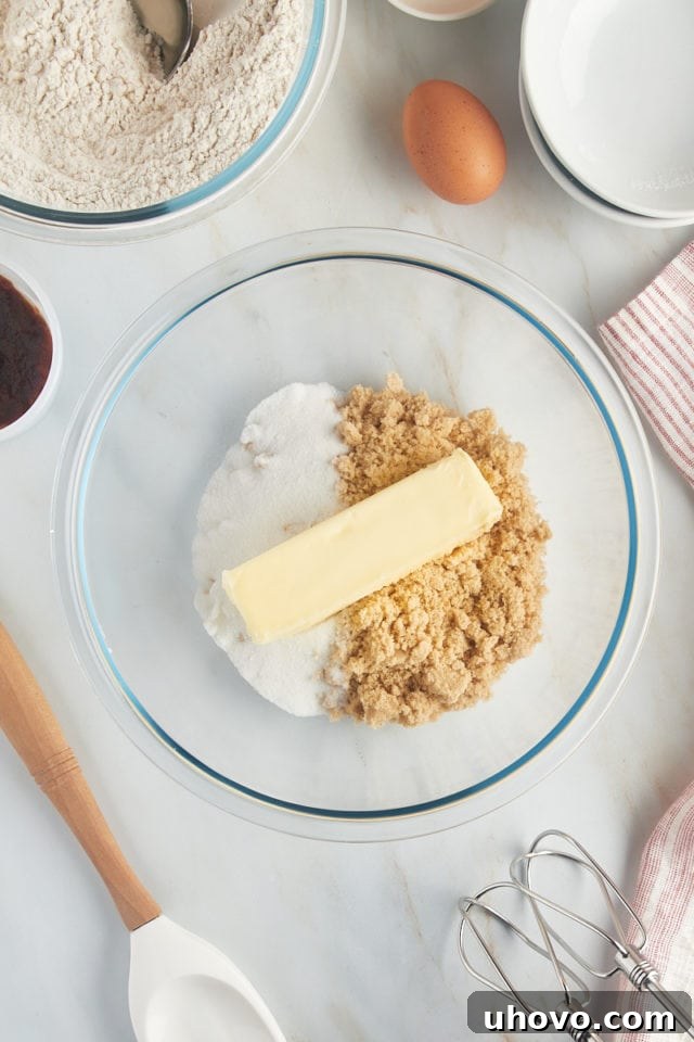 Overhead view of sugar, brown sugar, and butter in a glass mixing bowl.