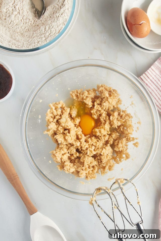 Overhead view of egg and vanilla extract added to creamed butter and sugar.