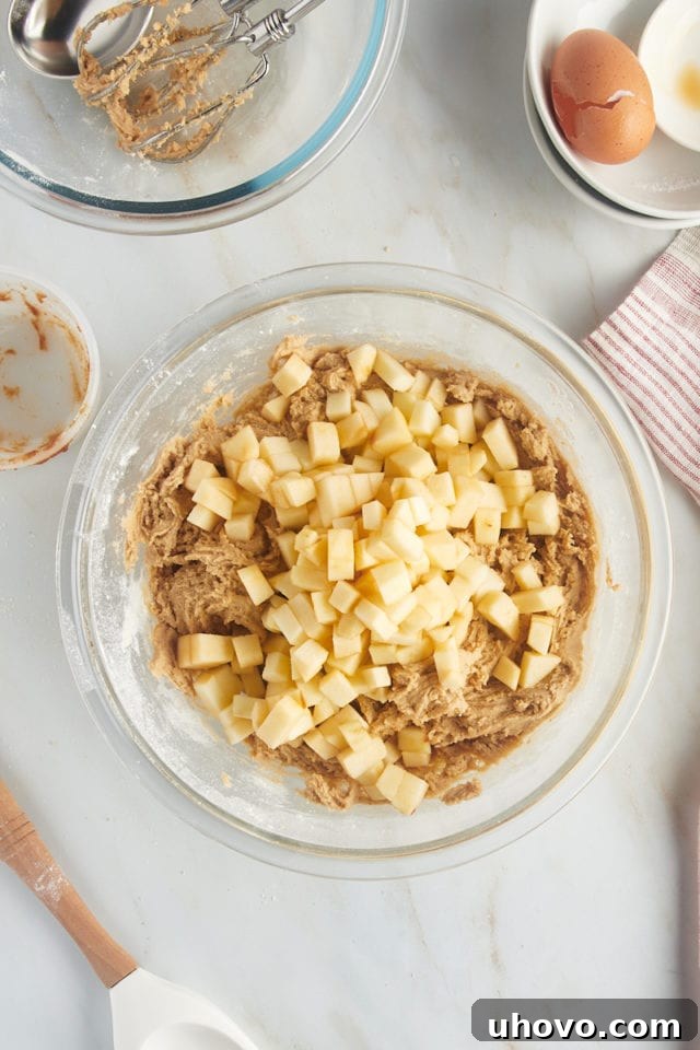 Overhead view of chopped apples added to cookie dough.