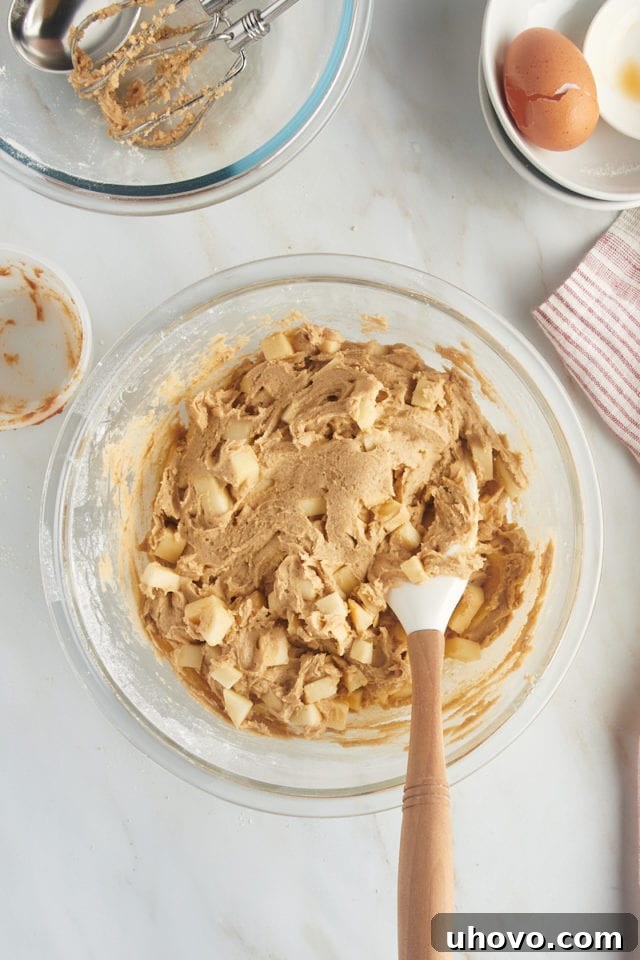 Overhead view of mixed crumb-topped apple cookie dough in a glass mixing bowl.