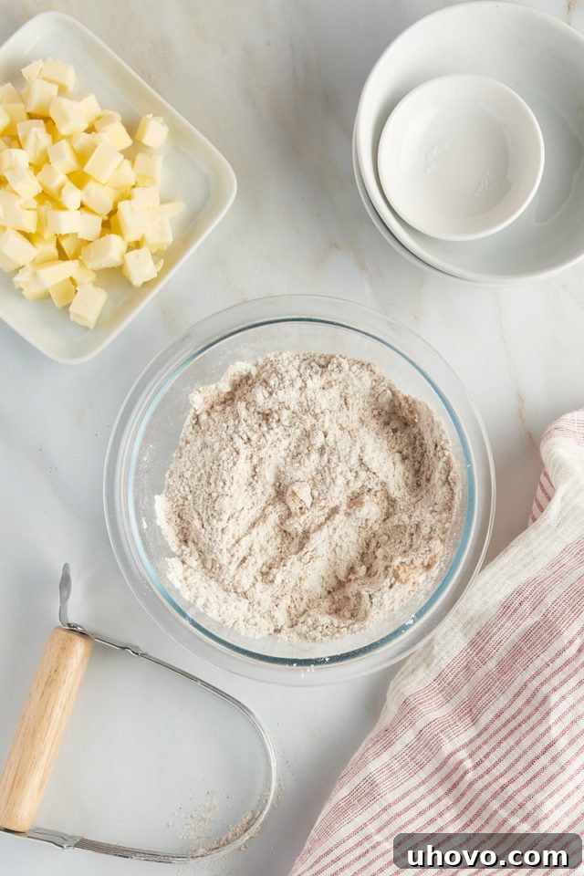 Overhead view of flour, brown sugar, cinnamon, and salt mixed in a glass bowl.