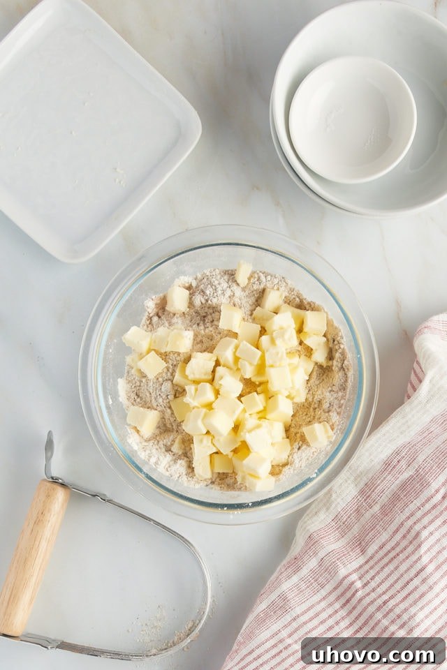 Overhead view of cubed butter added to dry ingredients for a crumb topping.